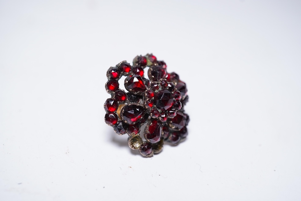 A suite of garnet and paste jewellery, comprising: a brooch, 5cm diameter; a bangle, inner circumference 16cm; two rings, sizes I and M; a pair of earrings, and a single earring, each set with rose-cut garnets; and a pai